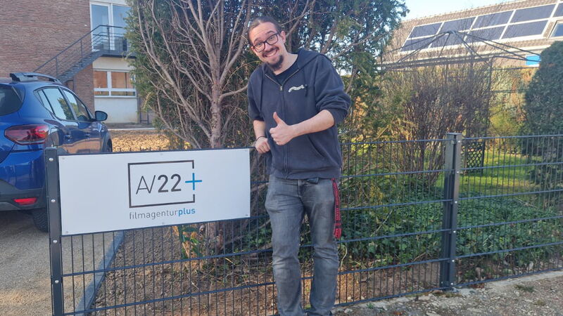 Jan Haller steht vor einem AV22-Firmenschild.